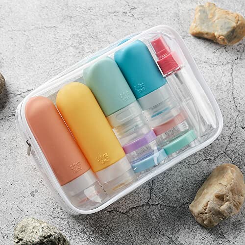 Clear bag with colorful travel-sized toiletry bottles on stone surface